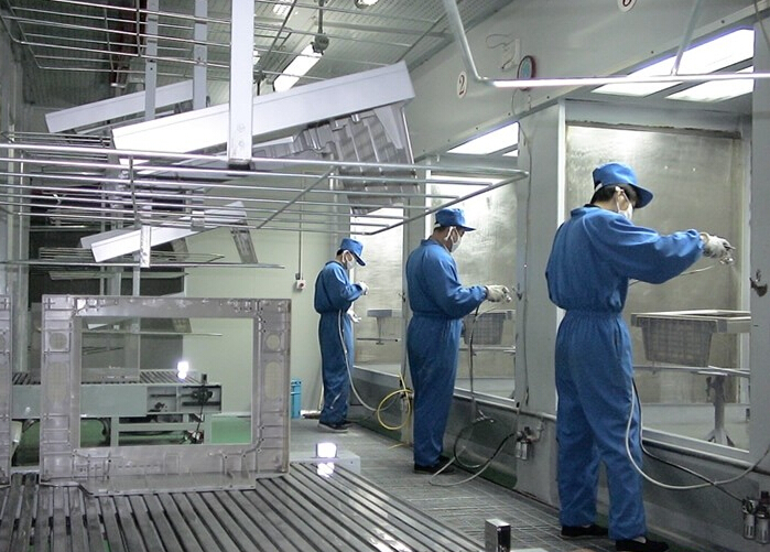 国内表面处理车间工人在喷涂线工位处理金属部件